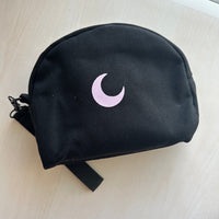 Brando Moon Bag in black canvas, three-quarter view in daylight, showing the gusset and wrist strap