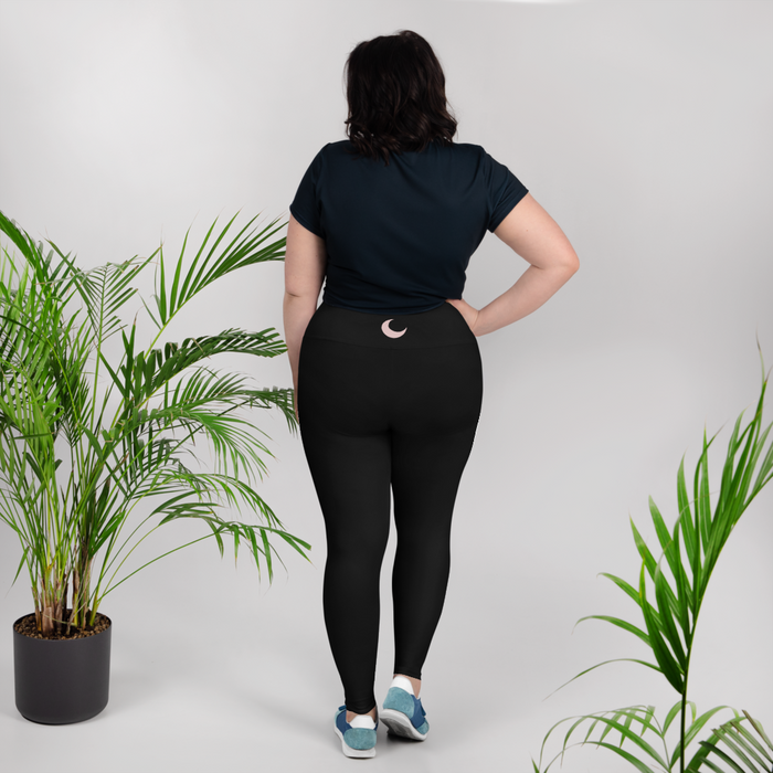 Black high-waist leggings worn back-to-camera, with a blush crescent moon at the waistband.