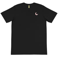 Black organic cotton tee laid flat, with a small blush crescent moon embroidered at the chest.
