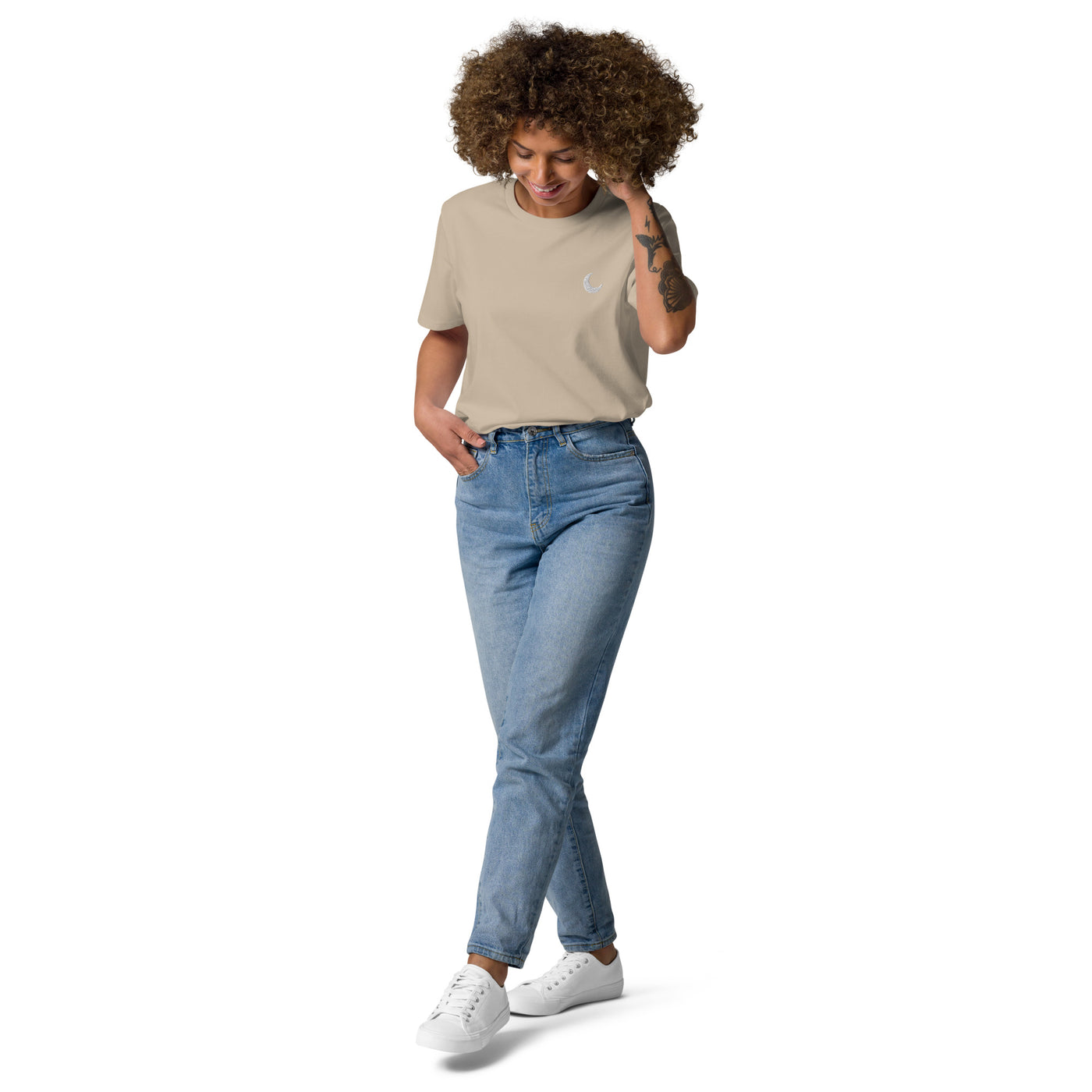 Sand-coloured organic cotton tee with a small white crescent moon at the chest, worn with light denim.